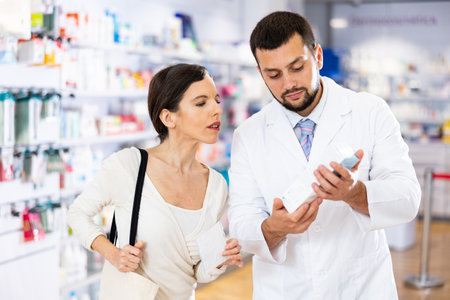 Female buyer consults the pharmacist which lotion or ointment to buy at pharmacyの写真素材