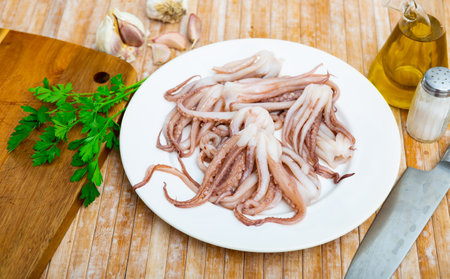 Raw squid tentacles on plate with condiments for cookingの写真素材