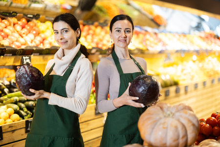 women staff with cabbage in hands in vegetable shopの写真素材