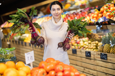 Woman choosing a beetroot in supermarketの写真素材