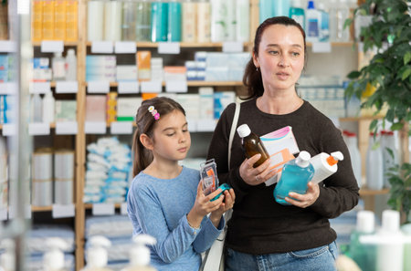 Woman with daughter choosing medicines and hygiene productsの写真素材