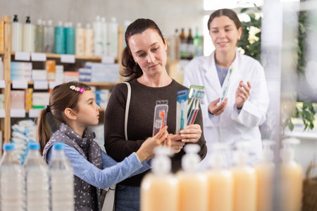 Middle-aged woman with daughter choosing toothbrush in drugstoreの写真素材