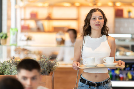 Young woman with coffee walking to table in cafeの写真素材