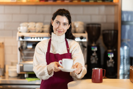 Girl cafe worker pours coffee from cezve coffee pot into cupの写真素材