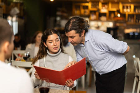Man waiter writes down girls order. Employee serve couple clients in cafeの写真素材