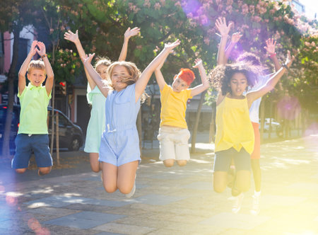 Cheerful preteen friends jumping on summer city streetの写真素材
