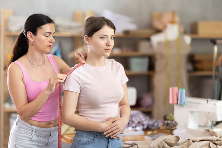 Woman tailor takes measurements from girl client