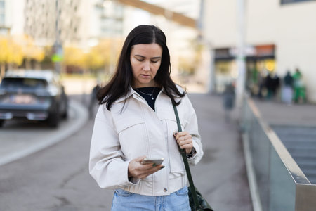 Female tourist girl gets lost in city center, looks at phone screen and tries to get directions