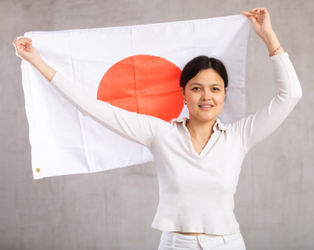 Smiling female fan of Japan cheers for winning holding flagの写真素材