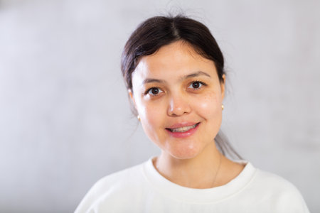 Closeup portrait of smiling young woman on gray backgroundの写真素材