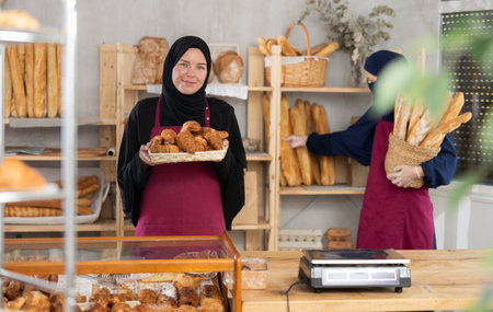 Seller of an oriental bakery in traditional muslim clothes with fresh hot croissants in handsの写真素材