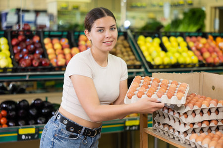 Young lady in supermarket buys chicken eggs.の写真素材
