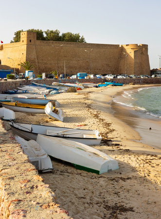 Medina of Hammamet on Mediterranean coast in Tunisia. Ancient fortress and fishing boats on beachの写真素材