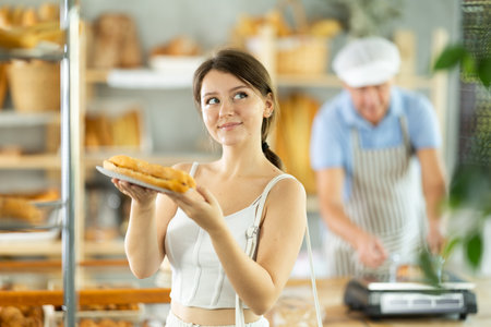 Portrait of a young girl with a bocadillo in her hands in the interior of private bakeryの写真素材
