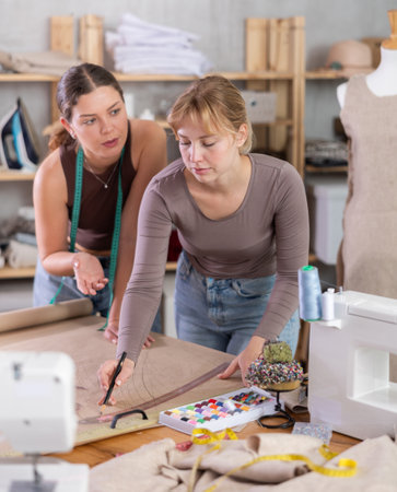 Female seamstresses drafting new clothing pattern on paper in sewing workshopの写真素材