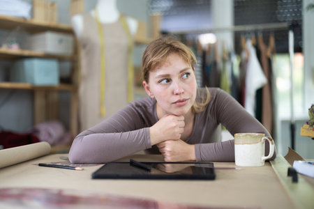 Tired dressmaker worker at tableの写真素材