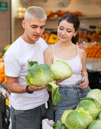 Married couple near vegetable stand in store choose cabbageの写真素材