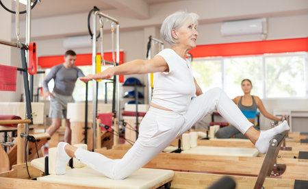 Elderly woman doing stretching on pilates machineの写真素材