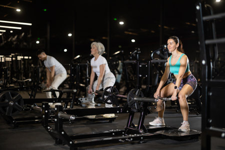 During training session in mini group of athletes, woman exercises on cable crossover machineの写真素材