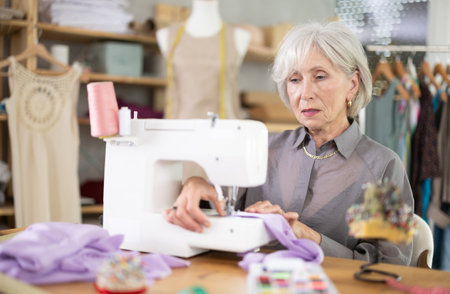 woman dressmaker sews on a machine in a workshopの写真素材