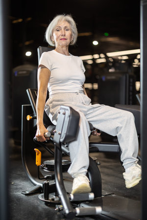 Older woman training on hip abduction machine at gym