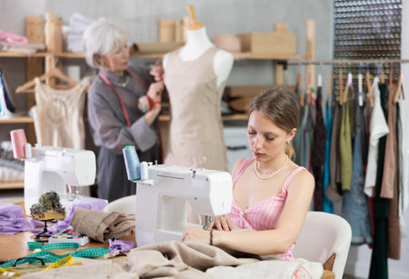 Young woman sews on machine female assistant sews on mannequinの写真素材