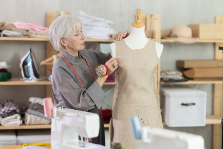 Woman seamstress adjusts clothes on mannequinの写真素材