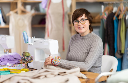 Woman tailor sews clothes in sewing machineの写真素材