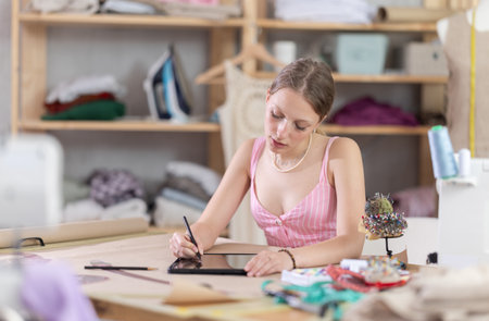 woman stands with a tablet in her hands in a sewing workshopの写真素材