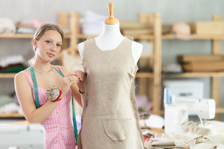 Positive young female dressmaker working with mannequinの写真素材