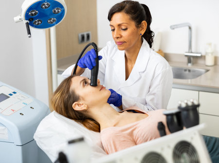 Hispanic woman beautician doing needle-free mesotherapy for young woman