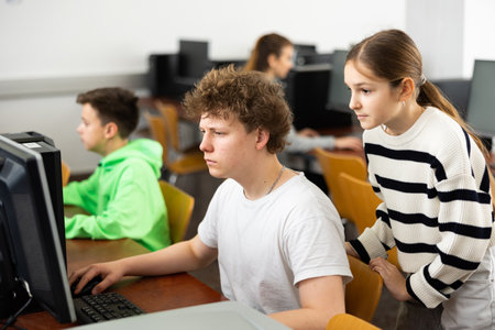 Teenagers help each other during classes in computer classの写真素材