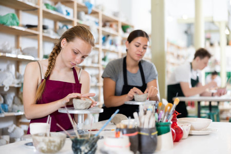 Teenage girl sculpts ceramic product in ceramic workshop