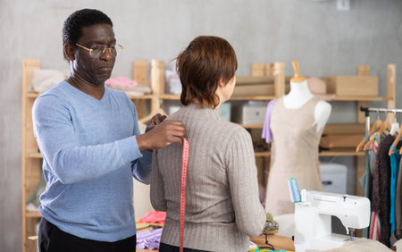 Tailor measuring female client in sewing studio for custom garmentの写真素材