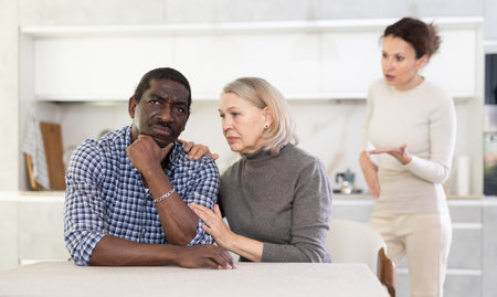 Elderly woman calms man during quarrel with adult womanの写真素材