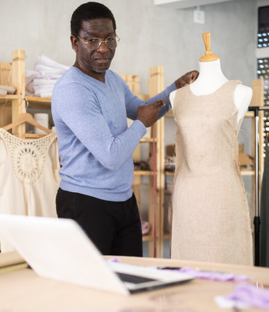 Fashion designer consulting online while adjusting dress on mannequinの写真素材