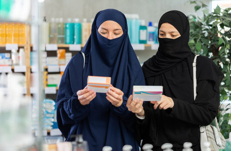 Two Muslim women comparing medicine boxes in pharmacy aisleの写真素材