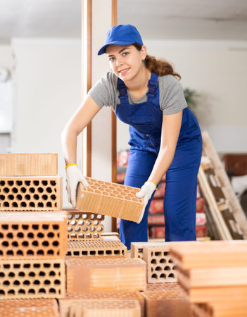 Female builder stacking bricks at construction site