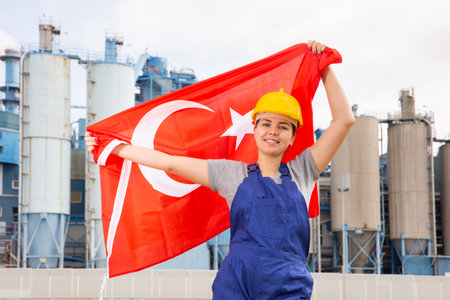 Happy woman waving flag of Turkey against the background of modern factoryの写真素材