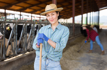 Asian female farmer posing in cowshed at the cow farm