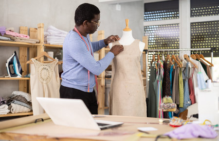 Male tailor sews new dress on a mannequin in sewing studioの写真素材