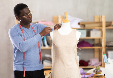 Experienced tailor shaping dress on mannequin in tailoring studioの写真素材