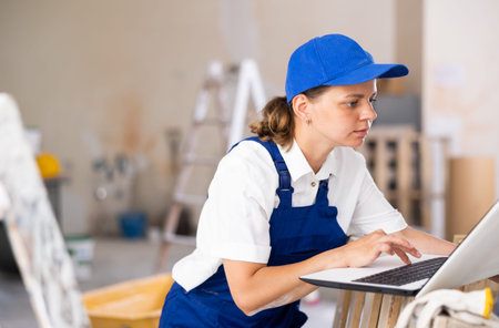 Portrait of a female builder who checks the work done using laptop