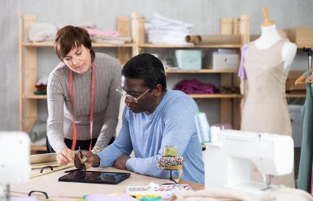 Two sewing workshop workers draw patterns on electronic tabletの写真素材