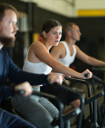 Sportive young girl doing air bike exercises in well-equipped gymの写真素材