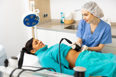 Doctor making rejuvenation electroporation procedure on abdomenの写真素材