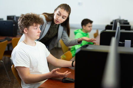 Teacher is dissatisfied with student during classes in the computer class of schoolの写真素材