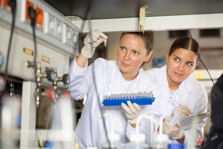 Adult and young female chemists examine liquid in laboratoryの写真素材