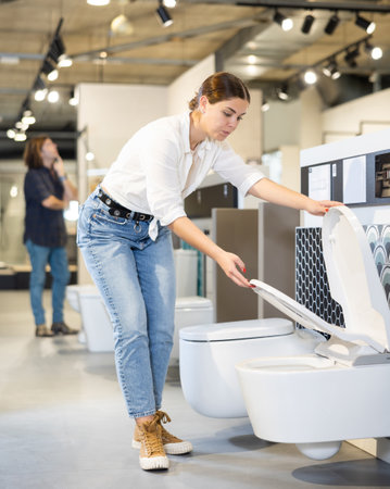 Female customer looking at white flush toilets on sale at modern store or shopping centreの写真素材