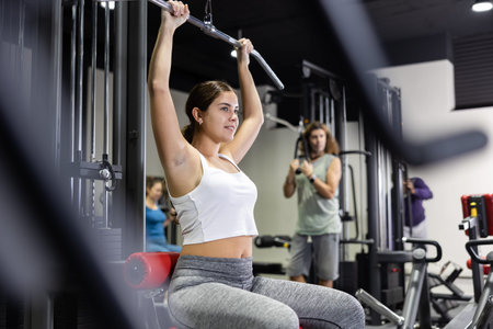 Woman is engaged in a simulator for development of back muscles